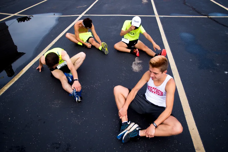 Four runners stretch in the Racine Family YMCA parking lot before the Lighthouse Run Saturday in Racine, Wisconsin.