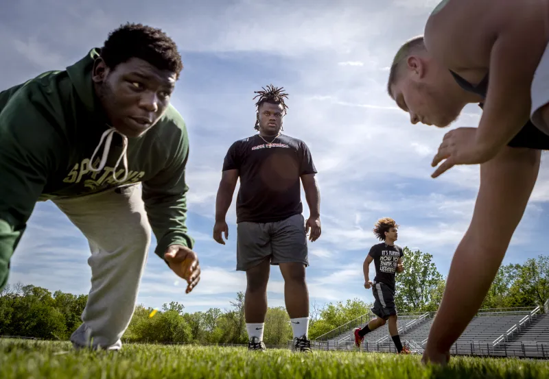 A 6-foot-1 and 288-pound Markus Bevier, Ypsilanti Community High School's defensive tackle, helps train underclassmen during football practice at Ypislanti Community High School on Thursday, May 24, 2018. Bevier spent part of his childhood living in a homeless shelter, and much of his time there practicing playing football for the love of the game. Davenport University just offered him a full football scholarship, but he plans to secure more as he nears college.