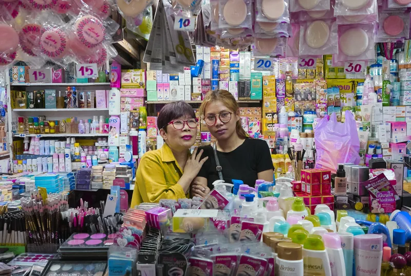 Boonsri Jinapunya, left and her daughter, Pang, stand behind the counter of Boonsri’s cosmetics stall in Chiang Mai's Chinatown. Born in 1960, Boonsri grew up in Chiang Mai, and has owned the small store for 36 years. Pang now attends a Universiry in Chiang Mai, and her mother helps her through school with the income she makes with her business.